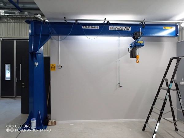 Pelarsvängkran med 1000 kg lyftkraft monterad vid arbetsstation i industrihall